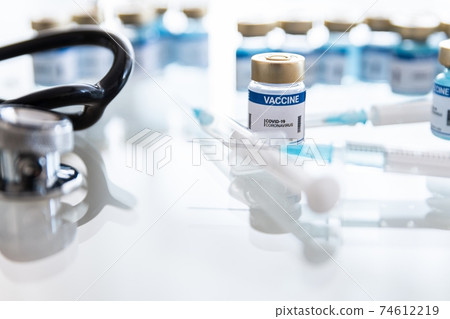 Coronavirus vaccine vials, ampoules and syringe on lab bench. 74612219