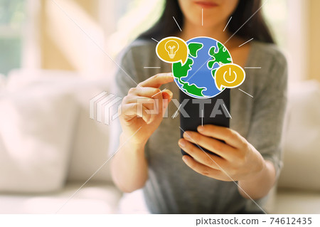Saving energy concept with woman using a smartphone Saving energy concept with woman using a smartphone 74612435