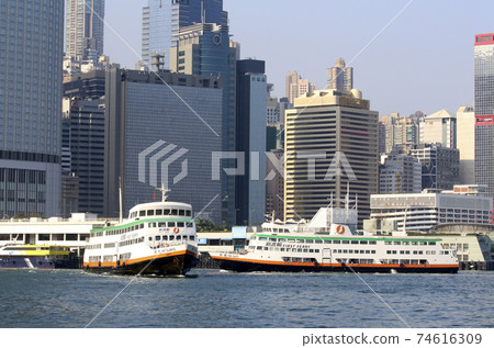 A ferry to a remote island called the first ferry in front of a skyscraper in Hong Kong Victoria Bay 74616309