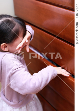 A girl who gets injured by pinching her hand when opening and closing a chest of drawers 74617656