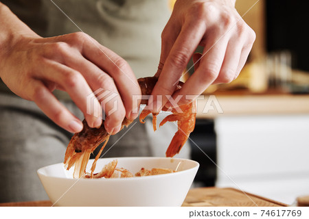 Woman cleaning shrimps for cooking. Process of hands peel shrimps shell Woman cleaning shrimps for cooking. Process of hands peel shrimps shell 74617769