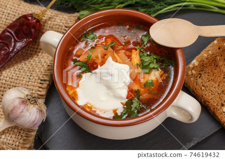 Ukrainian traditional borsch with wooden spoon on black background. Ukrainian traditional borsch with wooden spoon on black background. 74619432