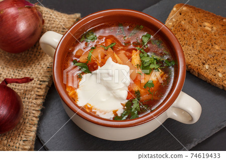 Ukrainian traditional borsch with bread on black background. Ukrainian traditional borsch with bread on black background. 74619433