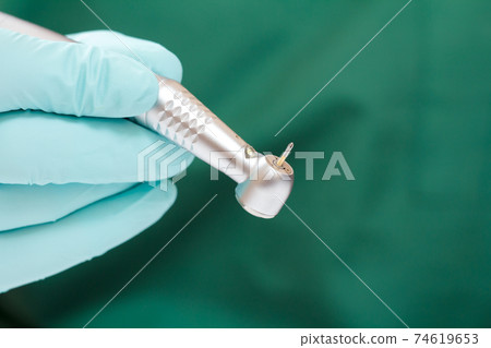 Dentist's hand in glove with dental handpiece. Dentist's hand in glove with dental handpiece. 74619653