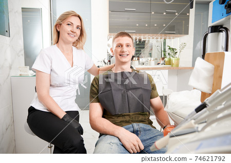Cheerful dentist and patient sitting in dental office. Cheerful dentist and patient sitting in dental office. 74621792