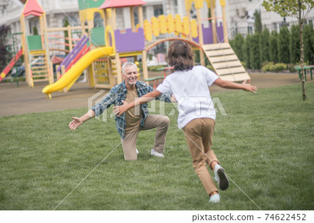 Boy running to his dads open arms and looking happy 74622452