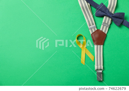 Suspenders, tie bow and Childhood cancer awareness ribbon on green background 74622679