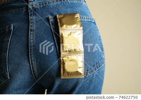 Female ass in jeans with condoms in back pocket, close up 74622750
