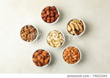 Bowls with different nuts on white textured background, top view Bowls with different nuts on white textured background, top view 74622842