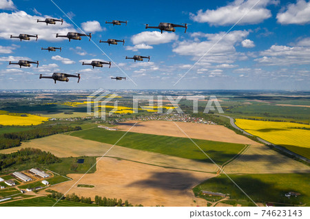 Drones fly over the fields. Natural landscape with drones and quadrocopters flying over it 74623143