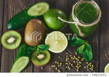 Blended green smoothie with ingredients on the stone board, wooden table 74623541