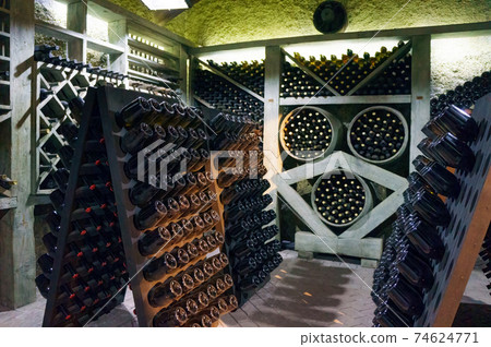 Wine cellar. The bottles on wooden shelves. Vintage storage of wine collection 74624771