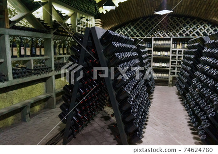 Wine cellar. The bottles on wooden shelves. Vintage storage of wine collection 74624780