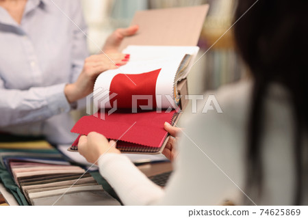 Seller shows visitor a red fabric in salon 74625869