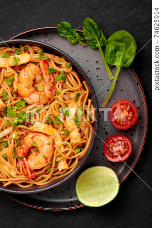 Mie Goreng in black bowl on dark slate table top. Indonesian cuisine prawn noodles vegetables dish 74625914