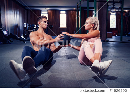 Fit couple doing abdominal ball exercise at gym 74626390