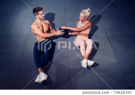 Fit couple doing abdominal ball exercise at gym 74626395