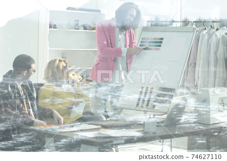 view through the glass wall. a group of fashion designers discussing new ideas view through the glass wall. a group of fashion designers discussing new ideas 74627110