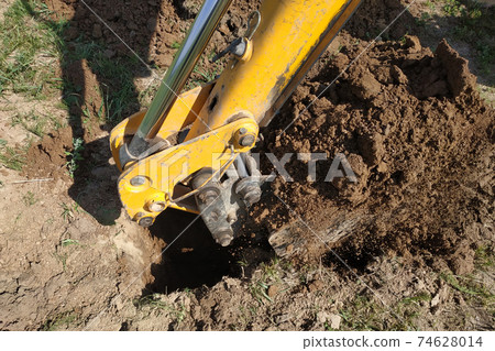The yellow excavator digs a trench, construction works by means of automobile equipment. 74628014
