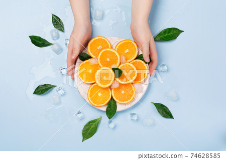 Natural healthy juicy organic orange slices and ice on blue background. Natural healthy juicy organic orange slices and ice on blue background. 74628585