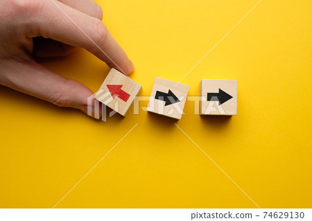 Concept of think differently - hand holds wooden cubes with arrows. 74629130