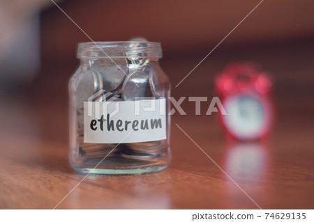 Savings concept for Ethereum - Glass jar with coins and inscription. 74629135
