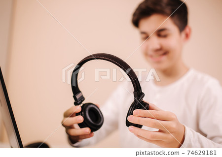 Close up steamer hold on-ear wireless headphones in hand and prepare for playing game. Teenage use laptop 74629181