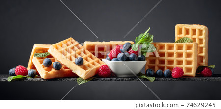Belgian waffles with  blueberries, raspberries  and fresh mint. 74629245
