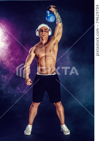 Muscular bodybuilder doing Exercise with kettlebell. Studio shot 74629784