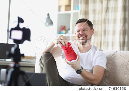Smiling man demonstrates sneaker on video camera 74630168