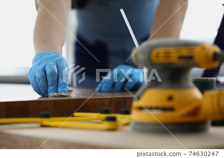 Gloved craftsman treats wooden surface with protective liquid Gloved craftsman treats wooden surface with protective liquid 74630247