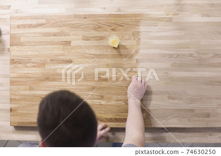 Man treats wooden surface of table with a protective varnish Man treats wooden surface of table with a protective varnish 74630250