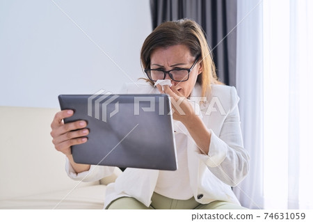 Sick business woman sneezing into handkerchief makes video call to doctor Sick business woman sneezing into handkerchief makes video call to doctor 74631059