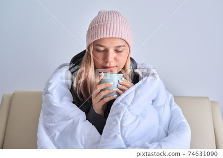 Cold autumn winter season, teenage girl sitting on sofa under warm blanket Cold autumn winter season, teenage girl sitting on sofa under warm blanket 74631090