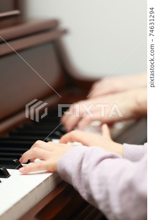 5-year-old girl and mom playing an upright piano 74631294