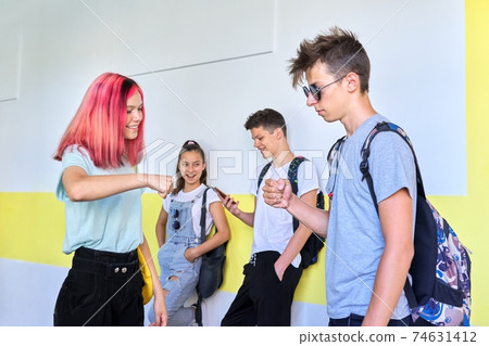 Teenagers in school greeting hand gestures when meeting Teenagers in school greeting hand gestures when meeting 74631412