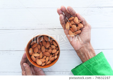 close up senior women hand holding a bowl on almond close up senior women hand holding a bowl on almond 74632287