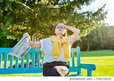 Symptoms of menopause in mature woman, female waves newspaper to cool off 74633020