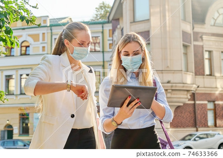 Business women wearing medical protective masks with digital tablet Business women wearing medical protective masks with digital tablet 74633366