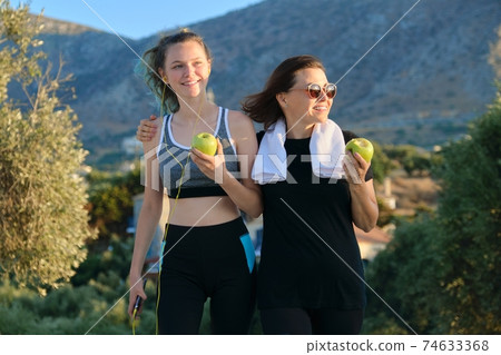 Athletic healthy family lifestyle, happy mother and teenage daughter eating apples Athletic healthy family lifestyle, happy mother and teenage daughter eating apples 74633368