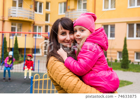 Mother with girl at playground. Woman holding she 74633875