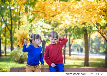 happy friends, schoolchildren having fun in autumn park among fallen leaves 74634123