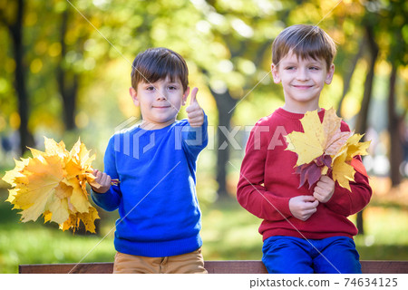 happy friends, schoolchildren having fun in autumn park among fallen leaves 74634125