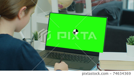 Little girl uses green screen chroma key laptop for learning, writes down useful information. Distance Learning, e-education, e-Learning, homeschooling concept. Little girl uses green screen chroma key laptop for learning, writes down useful information. Distance Learning, e-education, e-Learning, homeschooling concept. 74634369