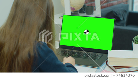 Child little girl lesson homework online at home. Distance education with children, online class or e-learning. Laptop web camera and make video call. Display with green screen. 74634370