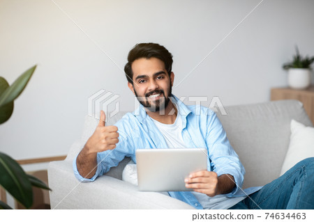 Handsome Arab Man Using Digital Tablet At Home And Showing Thumb Up Handsome Arab Man Using Digital Tablet At Home And Showing Thumb Up 74634463