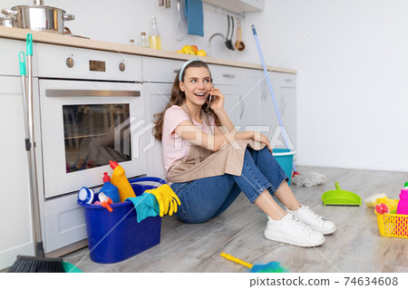 Cheerful woman speaking on cellphone during break from housework, enjoying phone conversation with friend at kitchen 74634608