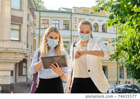 Business women wearing medical protective masks with digital tablet 74635577