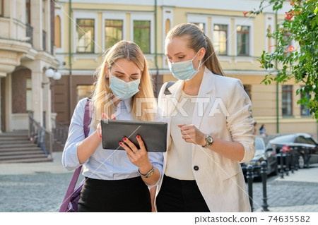 Business women wearing medical protective masks with digital tablet Business women wearing medical protective masks with digital tablet 74635582