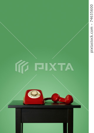 red landline telephone off the hook on a table 74635600